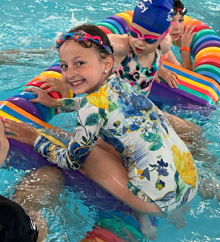 A girl playing with a water float toy inside a swimming pool