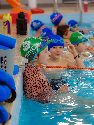 A group of kids wearing swim hats and goggles