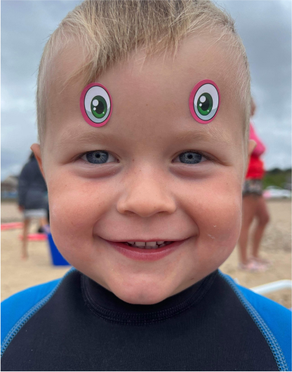 A little boy looking at the camera smiling in a wet suit